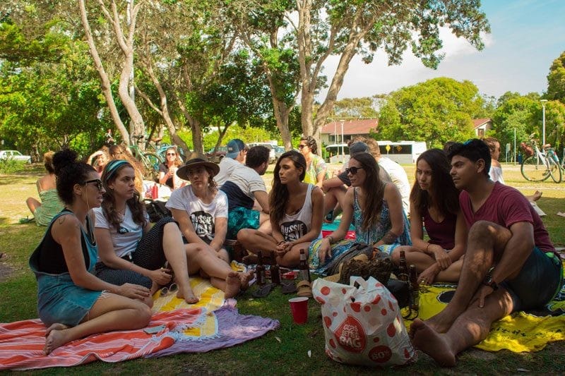 Ayuda para estudiar en Australia equipo chicas en barbacoa byron bay sentadas en el césped hablando